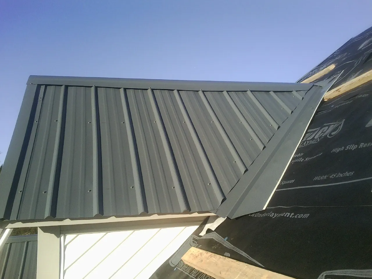 Gray metal roof panels going on over a garage gable in Florence