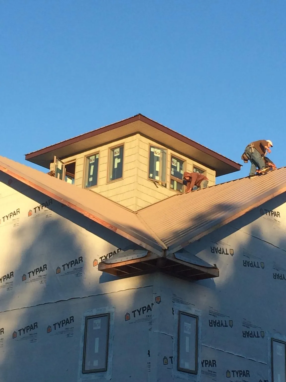Roofers working around a rooftop cupola on a new metal roof at sunset — Roof Waterproofing in Florence by Roofing Brothers